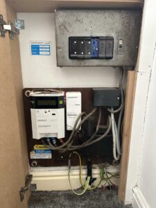 An open cupboard revealing an old rewireable domestic fuseboard and DNO equipment.